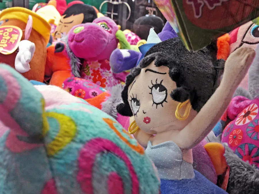 Peluche colorati accumulati dentro una macchina a premi